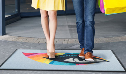 Logo-Outdoor - grey Logo-Outdoor mat with colourful elements in front of the entrance of a mall